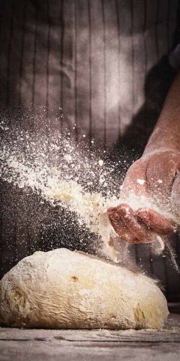 Baker kneeding dough with flour.