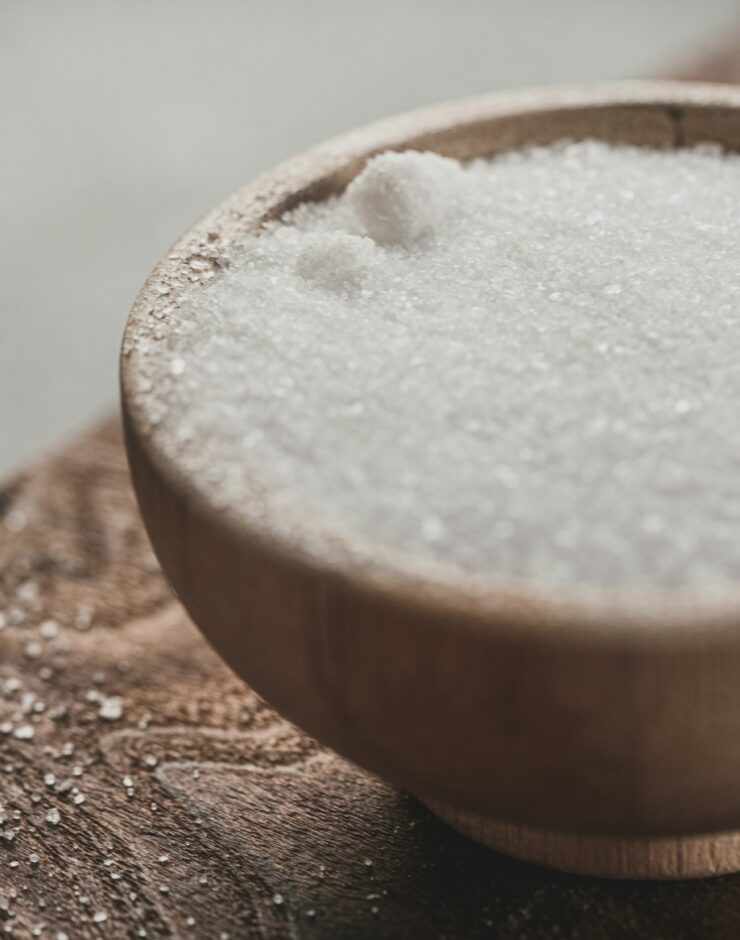 White crystalline powder in a wooden dish on a wooden table.