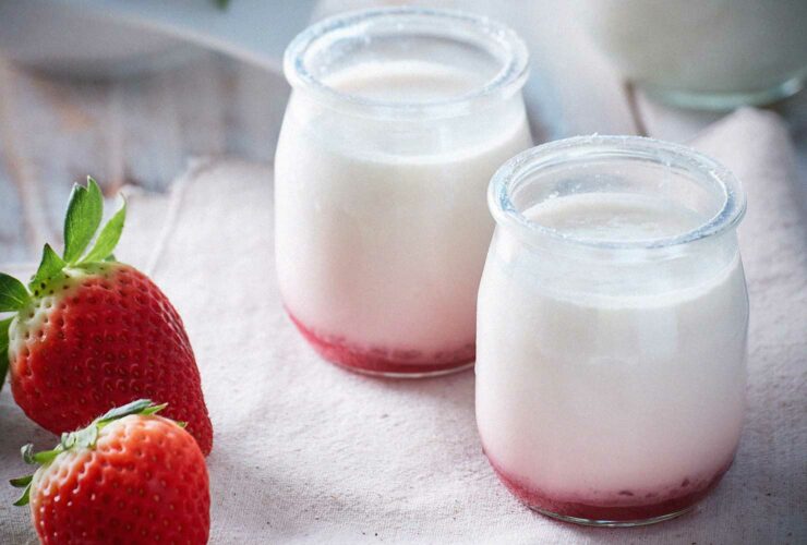 Strawberry yoghurts next to strawberries.