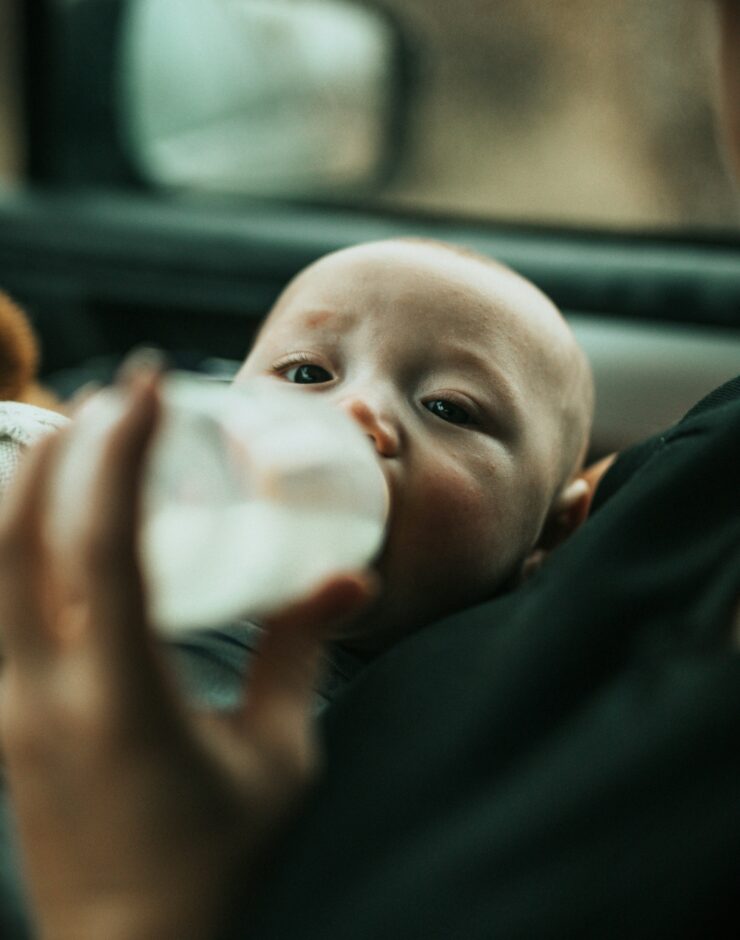 Baby being fed from a bottle in a car.