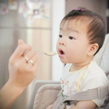 Baby being spoon fed baby food.