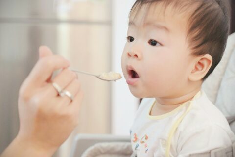 Baby being spoon fed baby food.