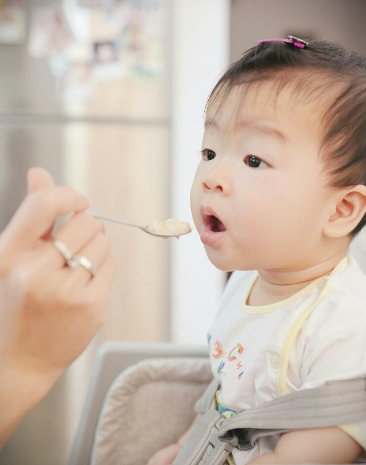 Baby being spoon fed baby food.