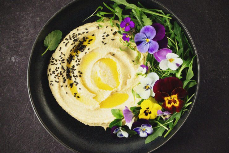 Bowl of houmous with decorative flowers.