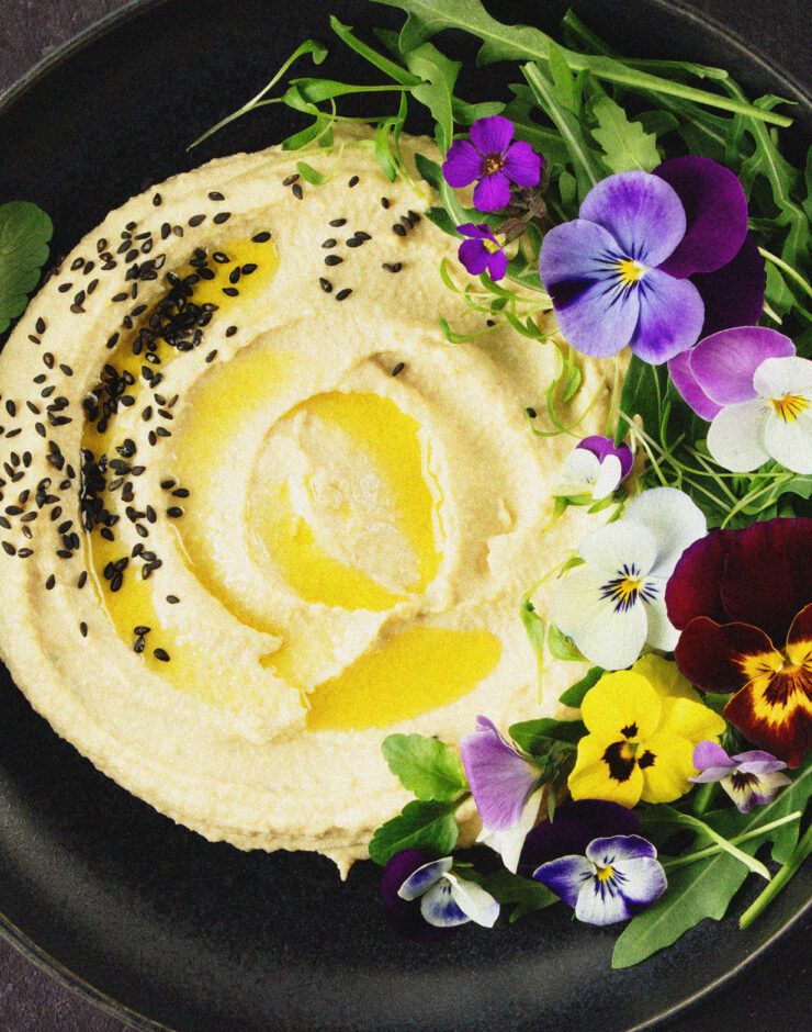 Bowl of houmous with decorative flowers.
