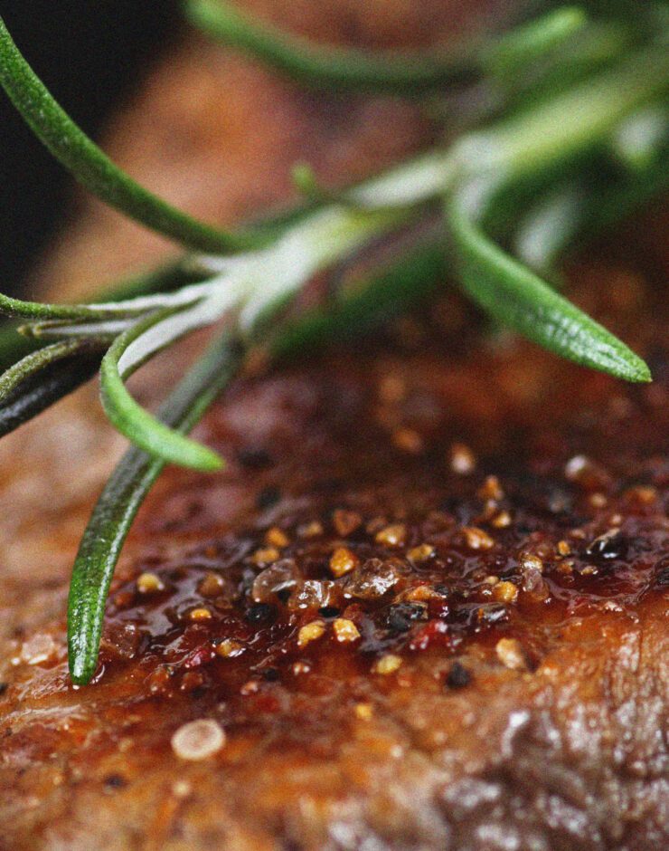 Cooked steak with rosemary sprig.